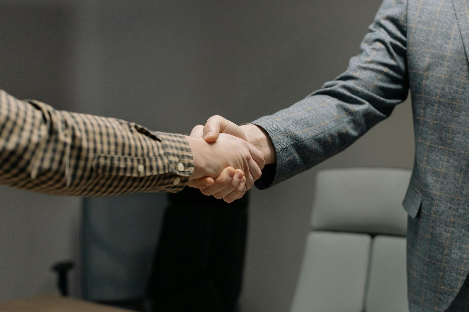 Close-up of two professionals shaking hands in an office, symbolizing successful business dealings.